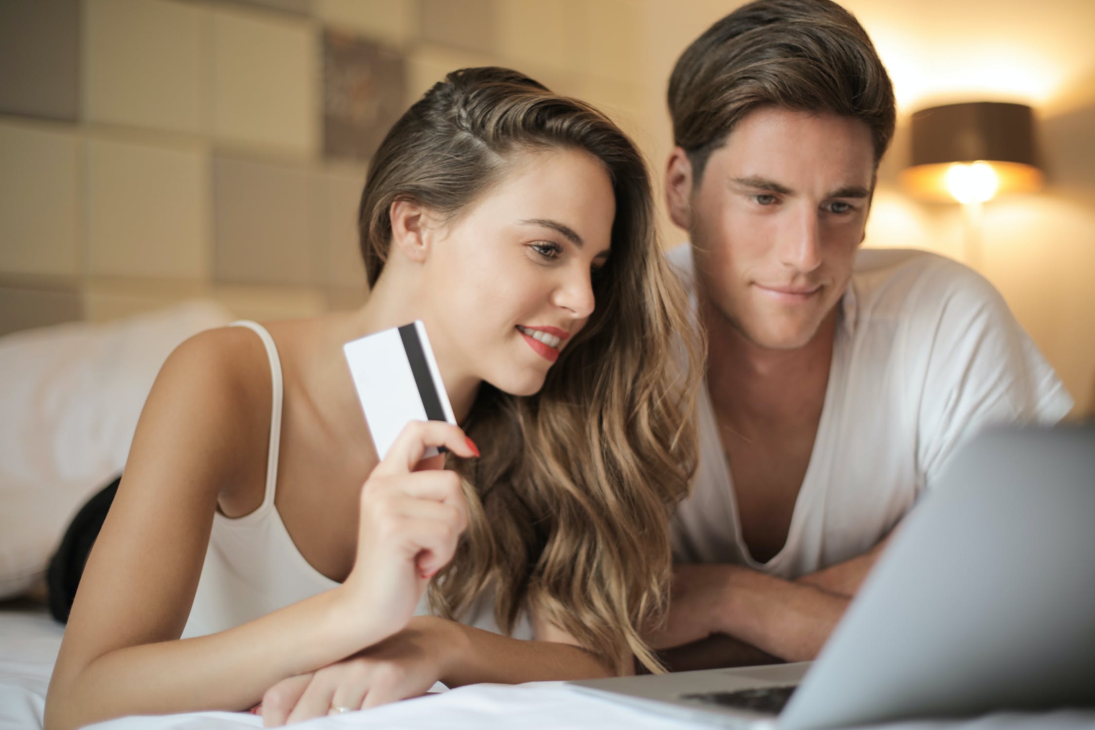 woman and man on bed on laptop online shopping